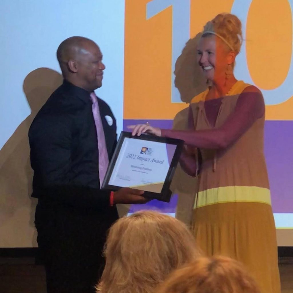A man receives an award from a woman at a 100+ Women Who Care - Madison meeting.
